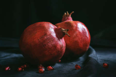 a few ripe whole pomegranates with a few berries on a dark backgroundの写真素材
