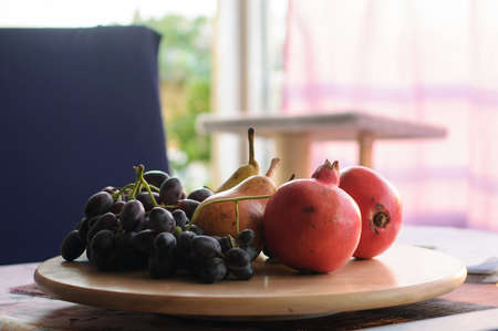 fresh red pomegranates grapes and pears on the tableの写真素材