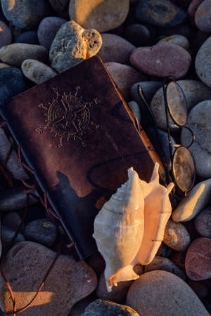 on the beach of pebbles a leather-bound book