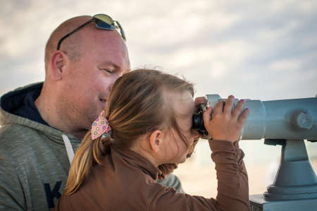 a father and his daughter are seen in public through binoculars