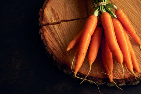 a bunch of clean young carrots on a wooden stand