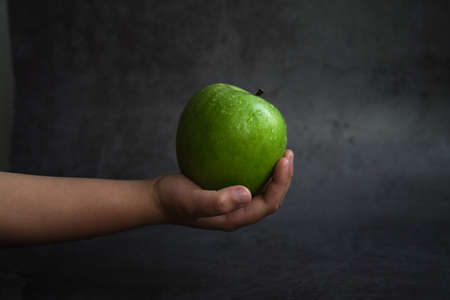 the girl holds a green apple in her handの写真素材