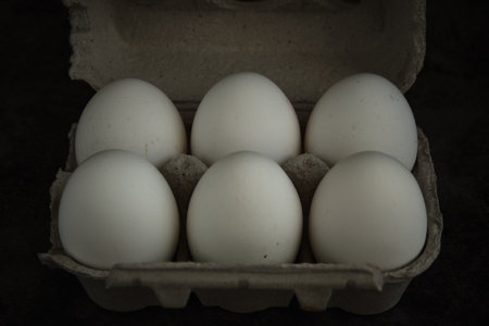 white fresh chicken eggs on dark background
