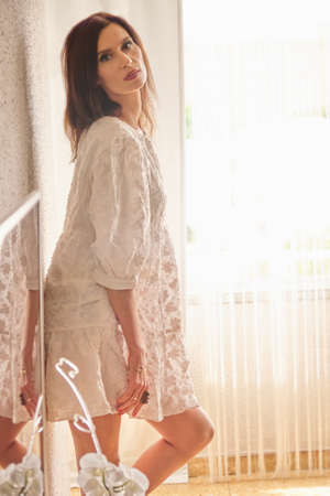 beautiful woman in a white dress against the wallの写真素材