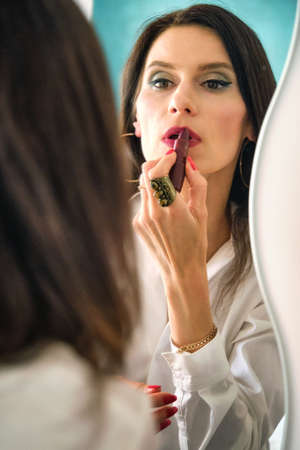 reflection a girl in the mirror paints her lipsの写真素材