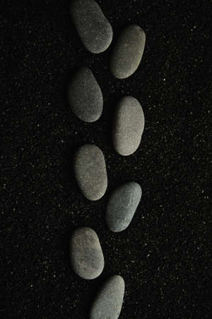small sea pebbles are laid out on a black background