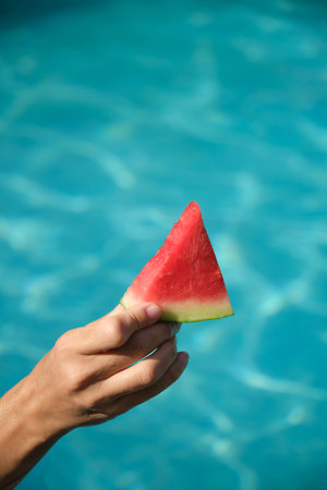 A piece of watermelon in his hand on a blue backgroundの写真素材