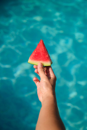 A piece of watermelon in his hand on a blue backgroundの写真素材