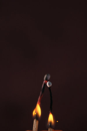 two lighted matches on a dark backgroundの写真素材