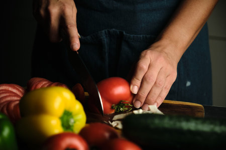 close-up of the cooks hands slicing tomatoesの写真素材