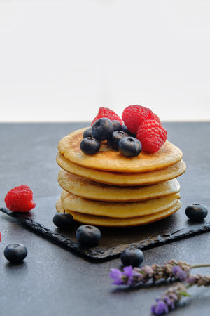 pancakes with berries and honey on dark background