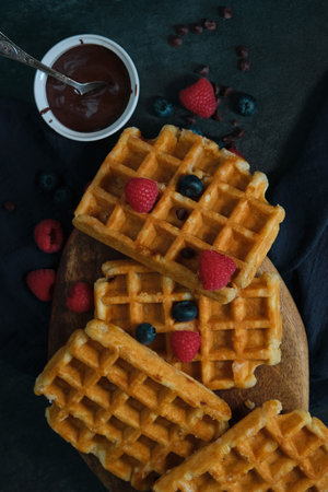 still life close up belgian waffles with chocolate raspberries and blueberries on a dark background...