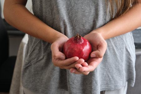 a red ripe pomegranate fruit in the hands of a girlの写真素材