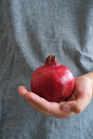 a red ripe pomegranate fruit in the hands of a girlの写真素材