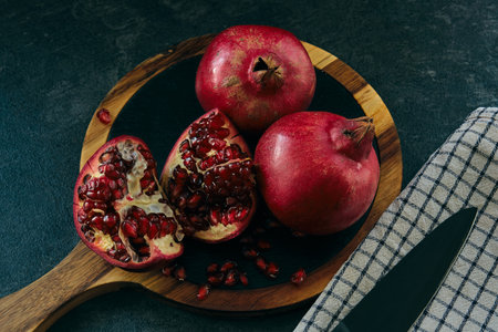 A few red ripe pomegranate fruits on a board on a dark backgroundの写真素材