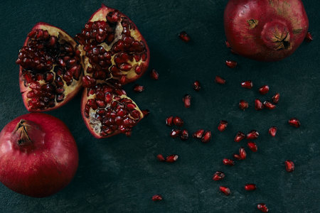 A few red ripe pomegranate fruits on a board on a dark backgroundの写真素材