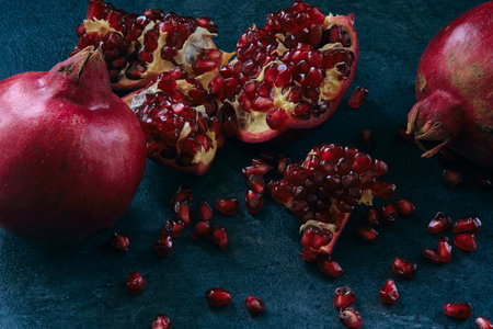 A few red ripe pomegranate fruits on a board on a dark backgroundの写真素材
