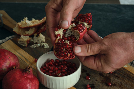 a man breaks and cleans open a ripe red pomegranateの写真素材