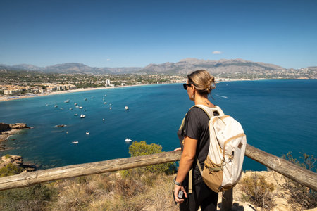 Young woman standing on high bank with backpackの写真素材