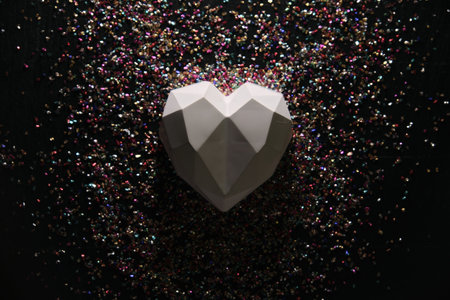 On a dark background in sequins lies a white heartの写真素材
