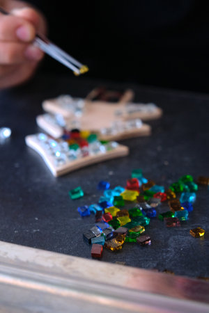 The child glues multi-colored glasses on a piece of woodの写真素材