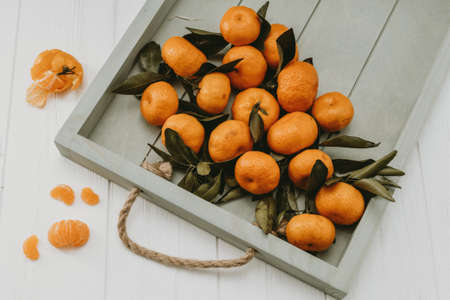 Christmas tangerines with leaves and tangerine slices on a light backgroundの写真素材