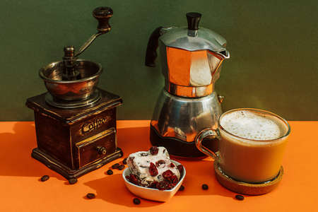 a cup of coffee with milk with a coffee maker and a coffee grinderの写真素材
