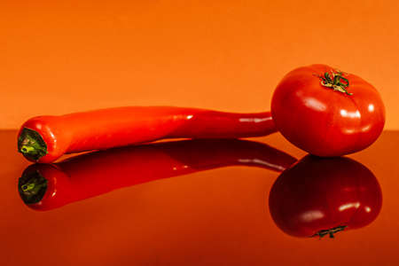 tomato and hot pepper on an orange backgroundの写真素材