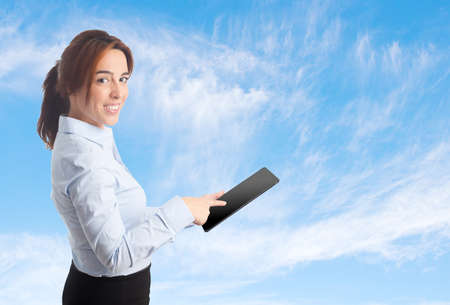 Business woman over clouds background. Using a tabletの写真素材