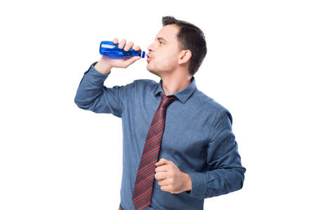 Man wearing a blue shirt and red tie. He is drinking from blue bottleの写真素材