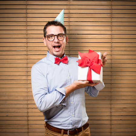 Man wearing a red bow tie and party hat. Holding gift. Looking happy.の写真素材