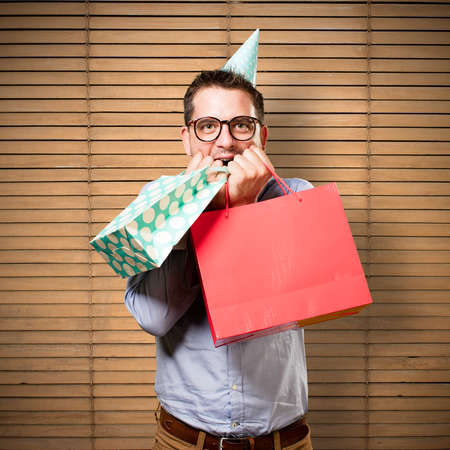 Man wearing a red bow tie and party hat. Holding gift. Looking happy.の写真素材