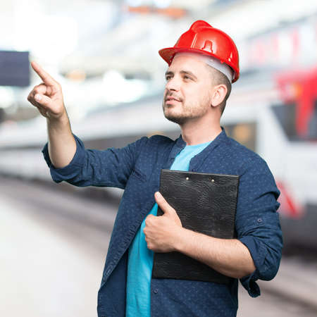 Young man wearing a blue outfit. Wearing red helmet. Pointing to something.