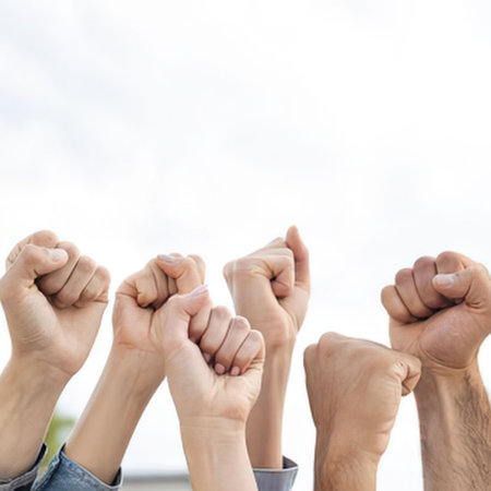 a group of people showing unity and solidarity by raising their fists in the air, a symbol of strength and togetherness, against a bright and cloudy sky