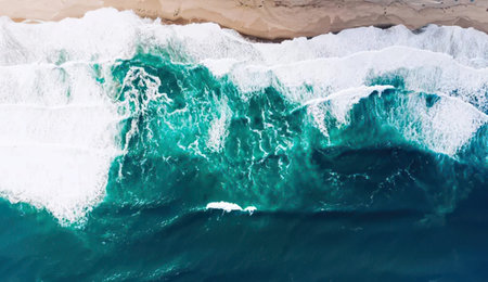 Aerial view of ocean waves breaking on sandy beach. Top view