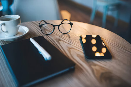 Close-up of smart phone and eyeglasses on wooden table