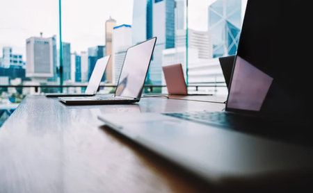 Laptop computer on wooden table with modern cityscape background, stock photo