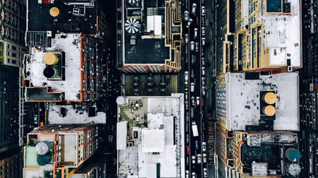 An overhead shot showing city streets filled with cars, buildings, and busy life.