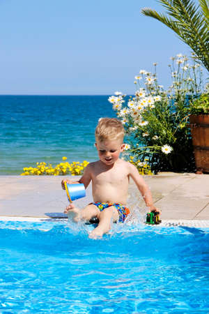 A child plays near pool. Sea and flowers at the background.の写真素材