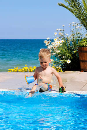 A child plays near pool. Sea and flowers at the background.の写真素材