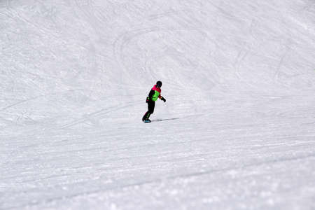 girl in a colorful suit is on a snowboard rides with mountainsの写真素材