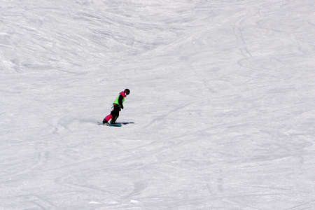girl in a colorful suit is on a snowboard rides with mountainsの写真素材