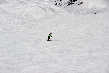 girl in a colorful suit is on a snowboard rides with mountainsの写真素材