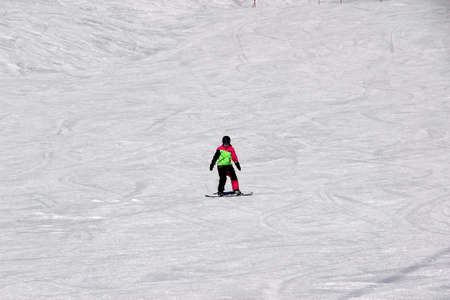 girl in a colorful suit is on a snowboard rides with mountainsの写真素材