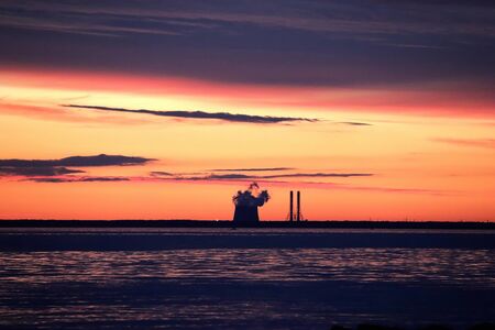 red sunset over sea with the powerplant on the horizonの写真素材