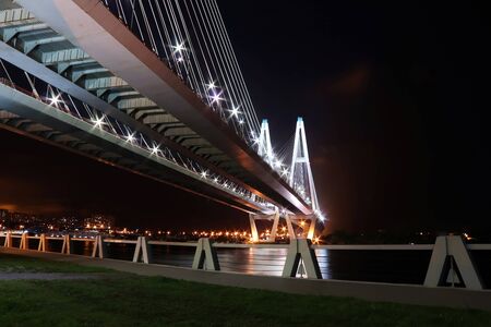 cable-stayed bridge over the river at night with colorful bright lighting