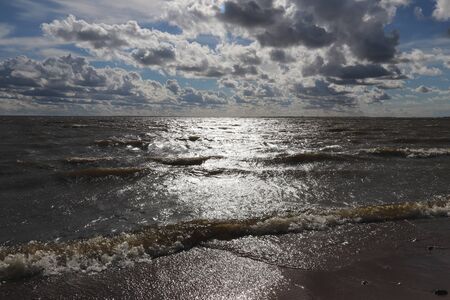 contrast blue sky with clouds over the sea and a sunny path on the waterの写真素材