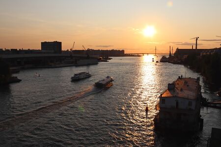 orange sunset over the river with a big bridge and boatsの写真素材