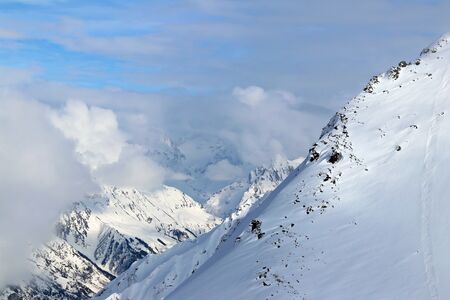 Snowy Mountains peaks in the clouds blue skyの写真素材