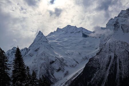 Snowy Mountains peaks in the clouds blue skyの写真素材